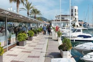 a marina with boats and people walking on a sidewalk at Apartamento en acantilado con wifi y aire acondicionado in Sitges