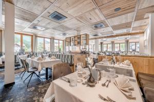a restaurant with white tables and chairs and windows at Hotel Grauer Bär in Sölden