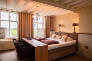 a bedroom with a bed and a desk and windows at Hotel Noorderhoofd in Veere