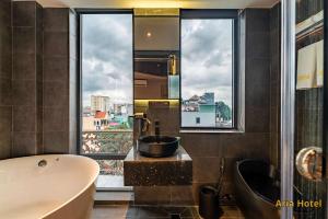 a bathroom with a tub and a sink and a window at Oria Hotel Gò Vấp in Ho Chi Minh City