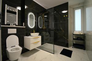 y baño con aseo, lavabo y espejos. en Apartamenty Marina na Wydmie, en Mrzeżyno 14 fotos más