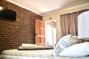 a bedroom with a brick wall and an open door at Delion Lodge in Koster