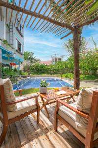 une terrasse avec 2 chaises, une table et une piscine dans l'établissement The Yen Villa Hoi An - Private Villa 7BR, à Thanh Ðông (1)