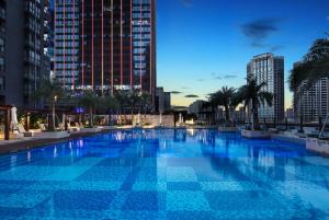 a large swimming pool in a city with tall buildings at Wyndham Grand Maoming in Maoming