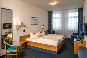 ein Hotelzimmer mit einem Bett und einem Stuhl in der Unterkunft Median Hotel Garni in Wernigerode