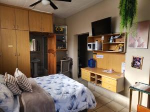 a bedroom with a bed and a desk with a tv at Primrose Accommodation in George