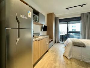 cocina con nevera de acero inoxidable y cama en Campo Belo Brand New Studio, en São Paulo