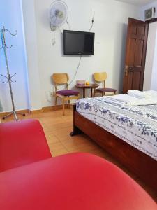 a bedroom with a bed and two chairs and a flat screen tv at Khách Sạn Bảo Long in Ho Chi Minh City