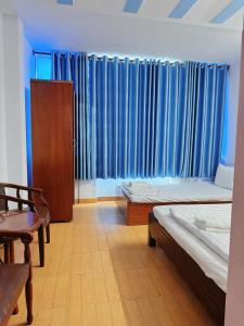 two beds in a room with blue curtains at Khách Sạn Bảo Long in Ho Chi Minh City +2 photos