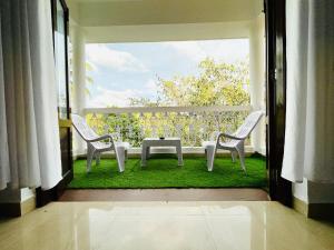 a balcony with two chairs and a table on the grass at The Driftwood Dan Studio Flat Colva, anirah in Colva