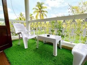 a balcony with two white chairs and a table at The Driftwood Dan Studio Flat Colva, anirah in Colva