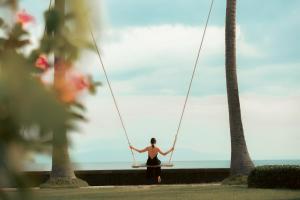 a woman on a swing at the beach at Nirwana Beach & Resort in Candidasa