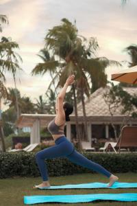 a woman doing a yoga pose on a yoga mat at Nirwana Beach & Resort in Candidasa +36 photos
