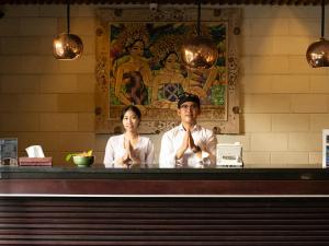 a man and woman sitting at a counter in a restaurant at The Bidadari Villas and Spa Umalas - Seminyak in Canggu