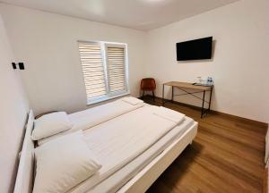 a bedroom with a bed and a desk with a television at Pakalnės sodyba in Skverbai