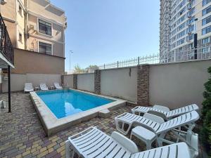 a swimming pool with chaise lounge chairs and a swimming poolvisorvisor at Odeska Astoria Arcadia Hotel in Odesa