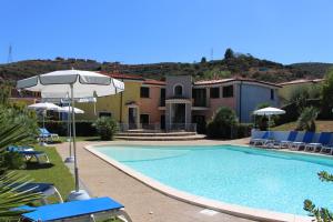 a swimming pool with an umbrella and chairs and a house at Appartamento 55 - Complesso Residenziale Terme di Casteldoria in Santa Maria Coghinas +39 photos