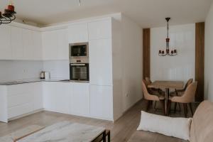 a kitchen with white cabinets and a table with chairs at Mitrovica View in Mitrovica