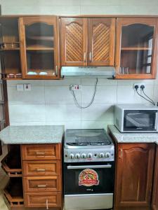 a kitchen with a stove and a microwave at Naura Home Stay in Nkunjila