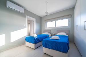 two beds in a hospital room with blue sheets at Majestic Sunset Salt Lake Views 300m From Beach in Larnaka
