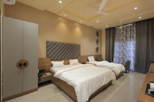 a bedroom with two beds and a flat screen tv at Hotel Black Harbour - A Unit of Om Shanti Inn in Bharatpur