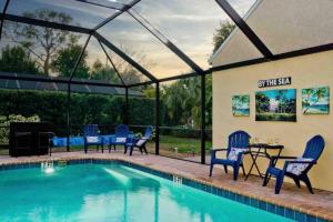 a swimming pool with chairs and a table next to a building at On Island! Private Pool Home-Walk to Great Beach! in Venice