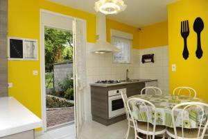 cocina con paredes amarillas, mesa y sillas en Le claujovin, en Méry-sur-Seine
