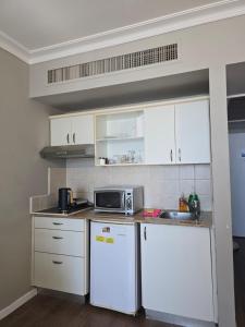 a small kitchen with white cabinets and a microwave at Sea Vacation in Haifa
