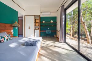 a bedroom with a bed and a large window at Rancho Coco Boutique Hotel Playa Negra in Río Sequito