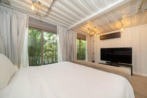 une chambre avec un lit blanc et une grande fenêtre dans l'établissement Contemporary Eden - Villa Jeladore, 5BR, Garden & Pool, near Laguna, à Ban Pak Lak