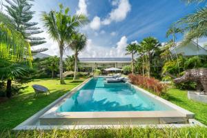 une piscine au milieu d'une cour avec des palmiers dans l'établissement Contemporary Eden - Villa Jeladore, 5BR, Garden & Pool, near Laguna, à Ban Pak Lak