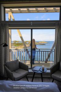 a woman standing on a balcony looking out at the ocean at Værlandet Havhotell in Hamna