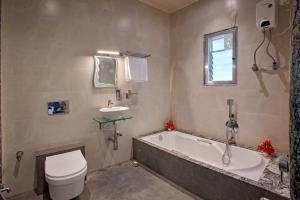 a bathroom with a tub and a toilet and a sink at Green House Resort by Green Apple Stays  +20 photos