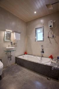 a large bathroom with a tub and a sink at Green House Resort by Green Apple Stays 