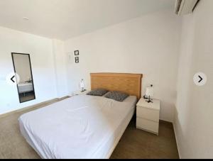 ein weißes Schlafzimmer mit einem Bett und einem Spiegel in der Unterkunft Vera Armony Natura FKK in Playas de Vera