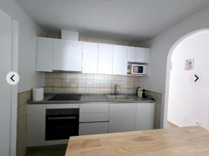 eine Küche mit weißen Schränken und einem Herd mit Backofen in der Unterkunft Vera Armony Natura FKK in Playas de Vera