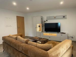 a living room with a brown couch and a flat screen tv at Pension Böhmer in Stolpen