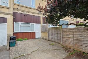 an empty driveway in front of a house with a fence at Chic Bath Flat for Couples with Free Parking! in Bath