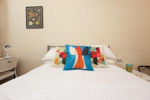 a bedroom with a white bed with colorful pillows at Chic Bath Flat for Couples with Free Parking! in Bath +23 photos