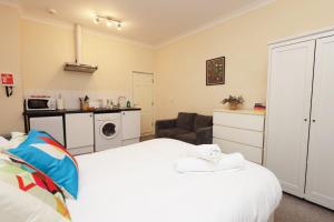 a bedroom with a white bed and a kitchen at Chic Bath Flat for Couples with Free Parking! in Bath