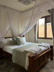a bedroom with a canopy bed with a window at Almond 7 in Gazi +5 photos