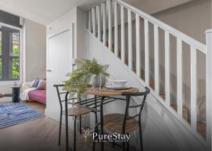 a dining room table with two chairs and a staircase at Stylish Flat in Central Leeds with Mezzanine Room Sleeps 4 by PureStay in Central Station