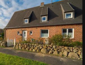 ein Backsteinhaus mit einem Steinzaun davor in der Unterkunft Room for one person in a shared apartment in Sylt