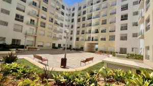 une cour dans un grand immeuble avec des bancs dans l'établissement N8 appartement, 3 Chambres Haut de Gamme, a Deux Pas de l Ocean et du Mall, à Rabat