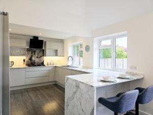 a kitchen with white cabinets and a marble counter top at The Gardens in Horley