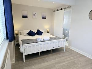 a bedroom with a white bed with blue pillows at The Gardens in Horley