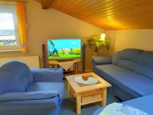 イルメナウにあるGästehaus Veronikaの青いソファ2脚とテレビのあるリビングルーム