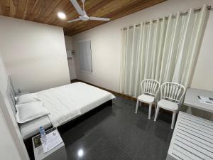 a hospital room with a bed and two chairs at Providence Guest House in Churāchāndpur