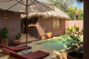 a pool with an umbrella and chairs and a house at Casa Moka in Puerto Escondido