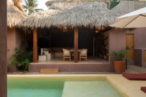 a house with a table and a thatch roof at Casa Moka in Puerto Escondido